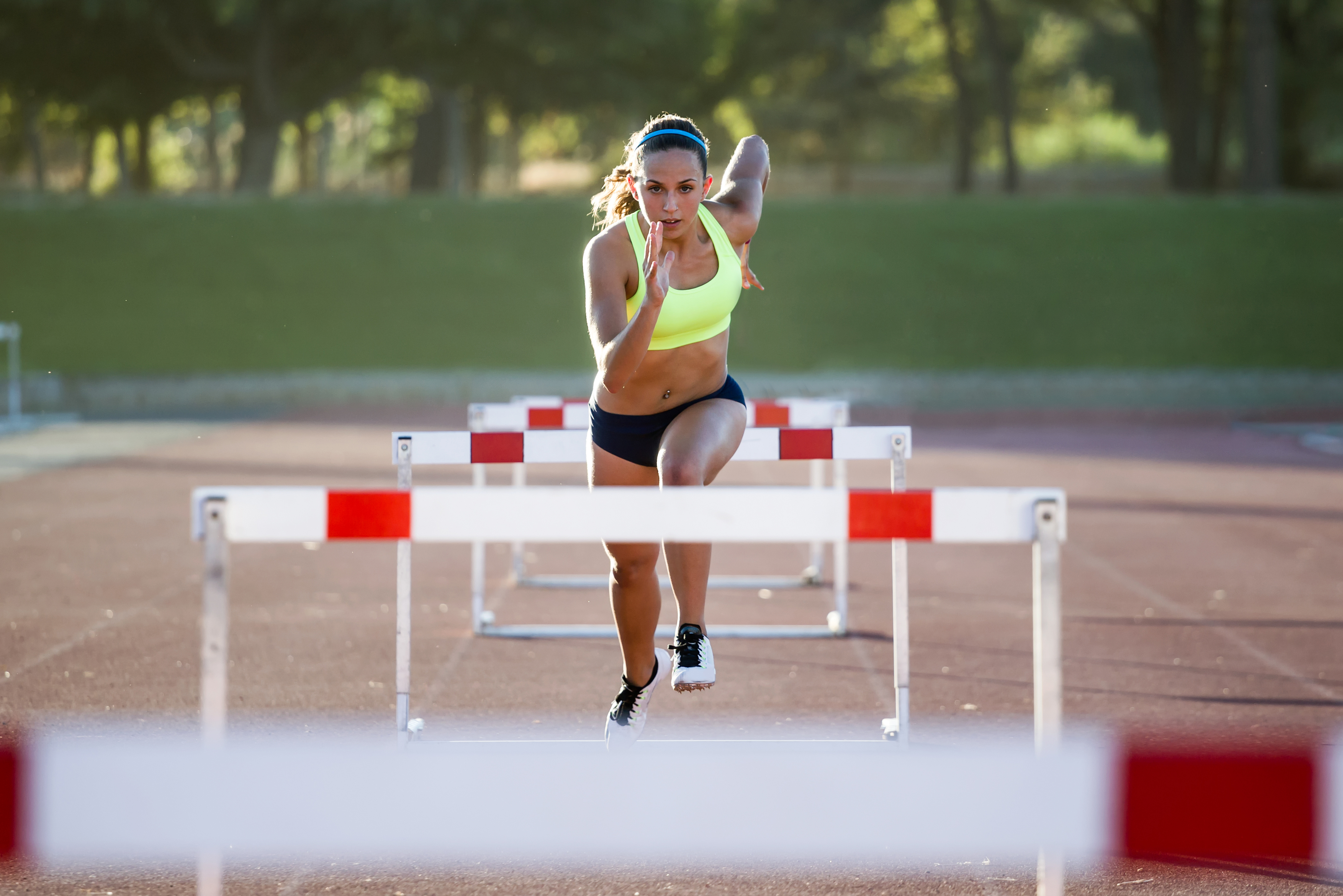 Female runner who is approaching a hurdle preparing to jump.