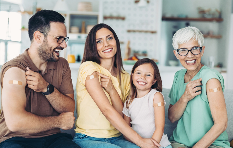 Family smiling together showing their vaccinated spot on right arm